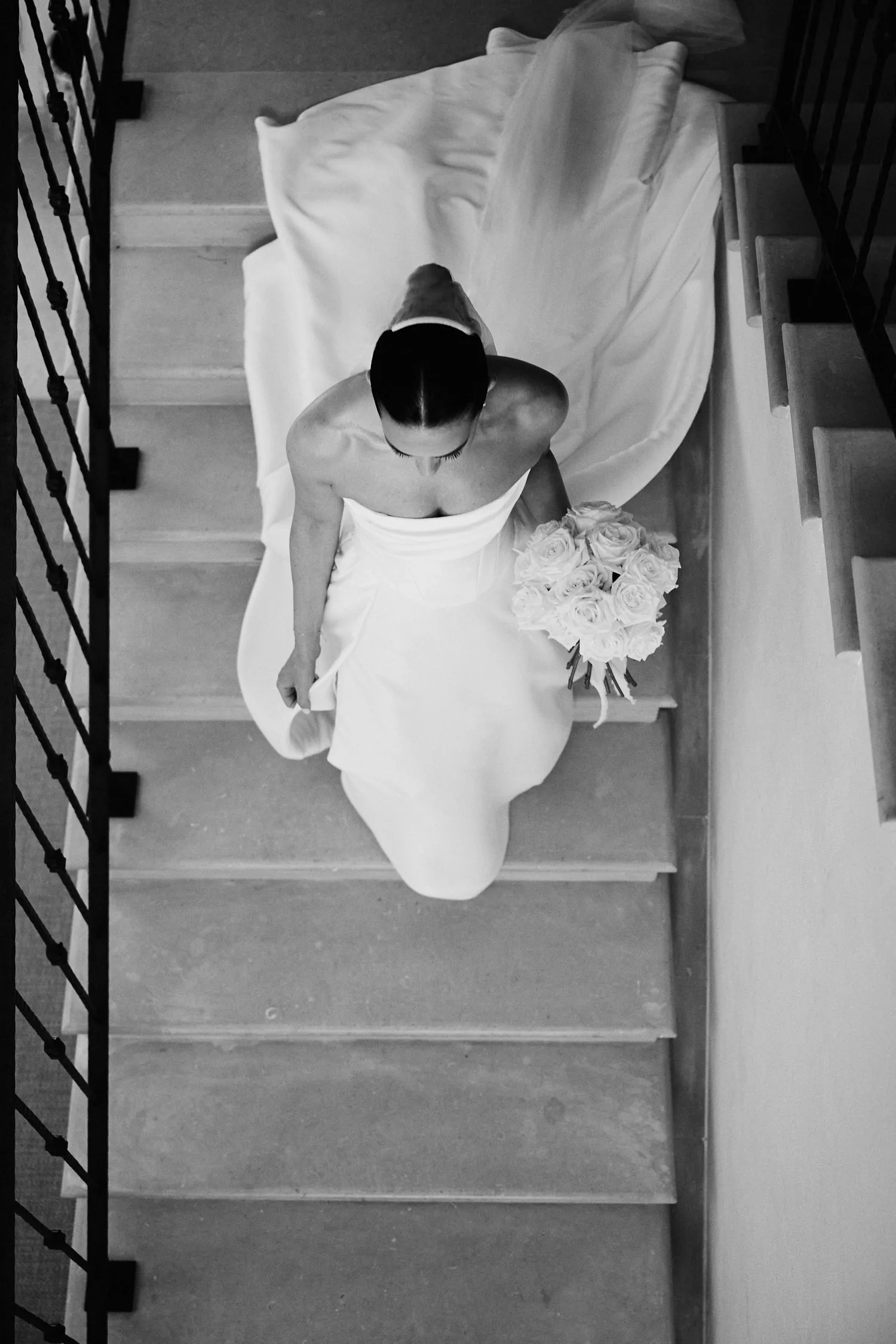 La sposa scende le scale vista dall’alto, in bianco e nero