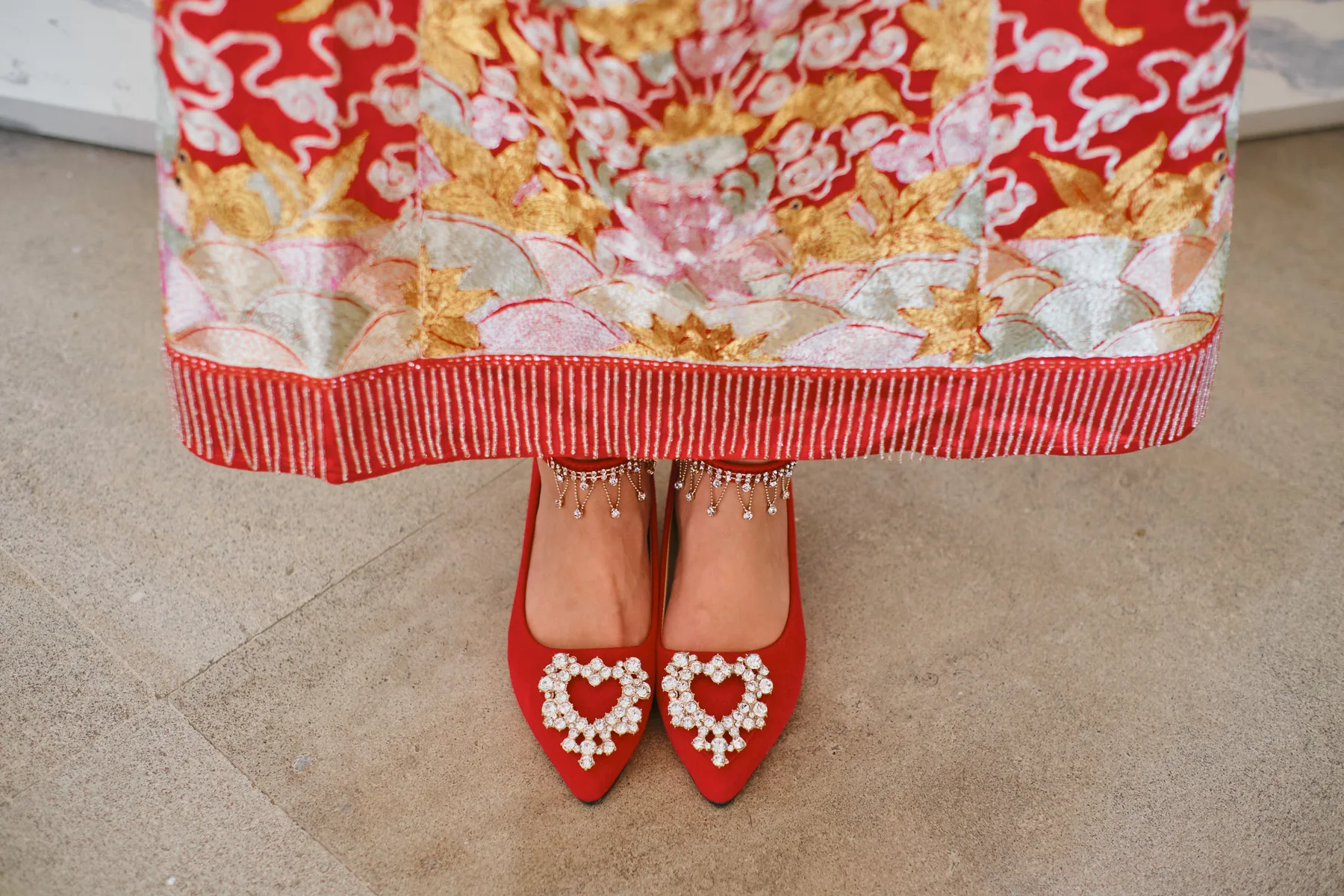 Le scarpe rosse della sposa sotto l’abito tradizionale ricamato
