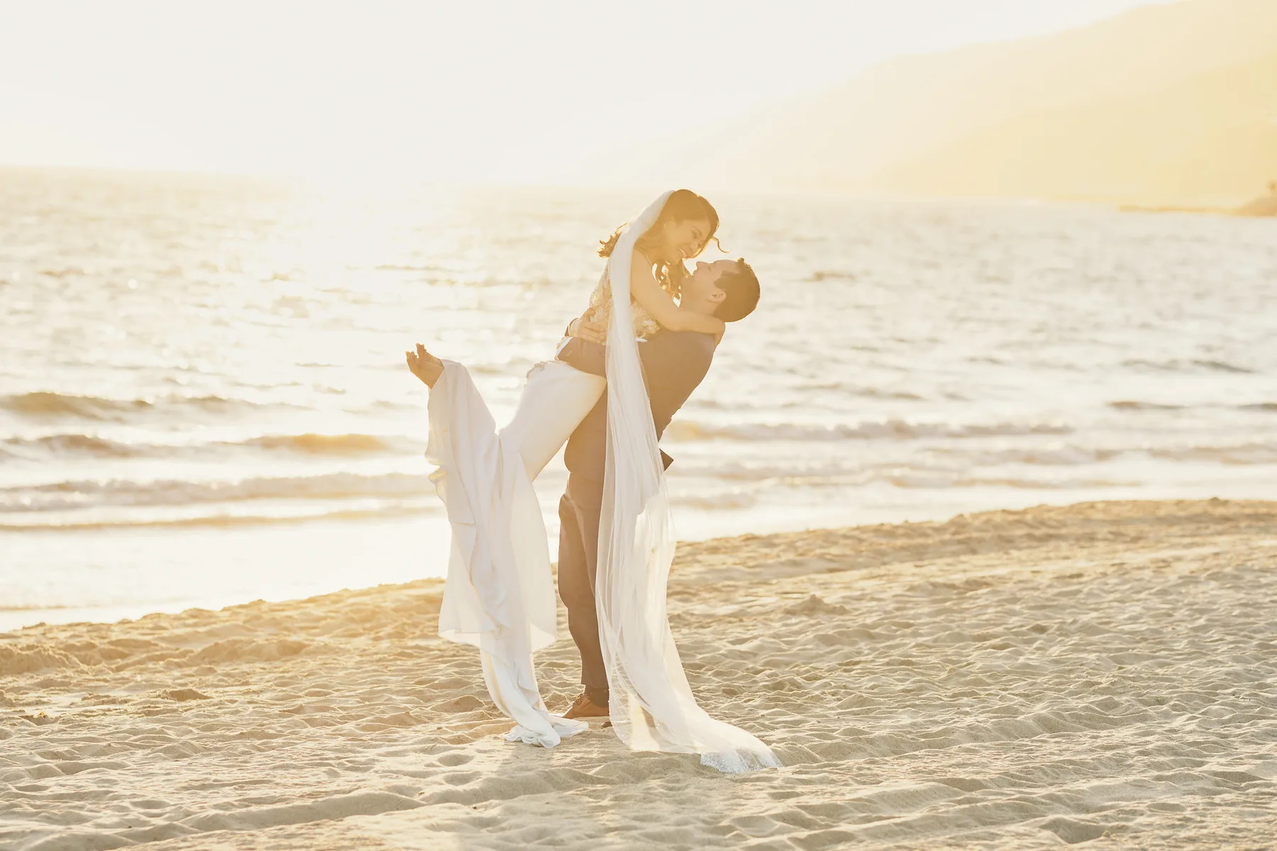 Lu e Drew si abbracciano sulla spiaggia al tramonto, a Los Angeles