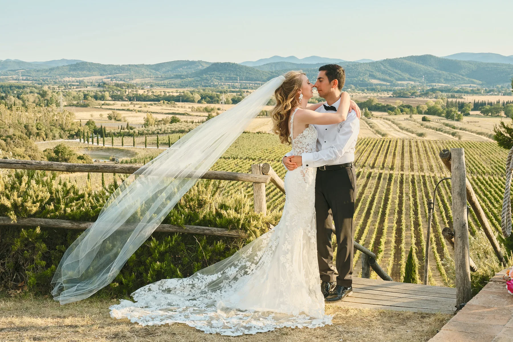 Pablo e Anna Marie si baciano sopra i vigneti toscani, con il velo nel vento