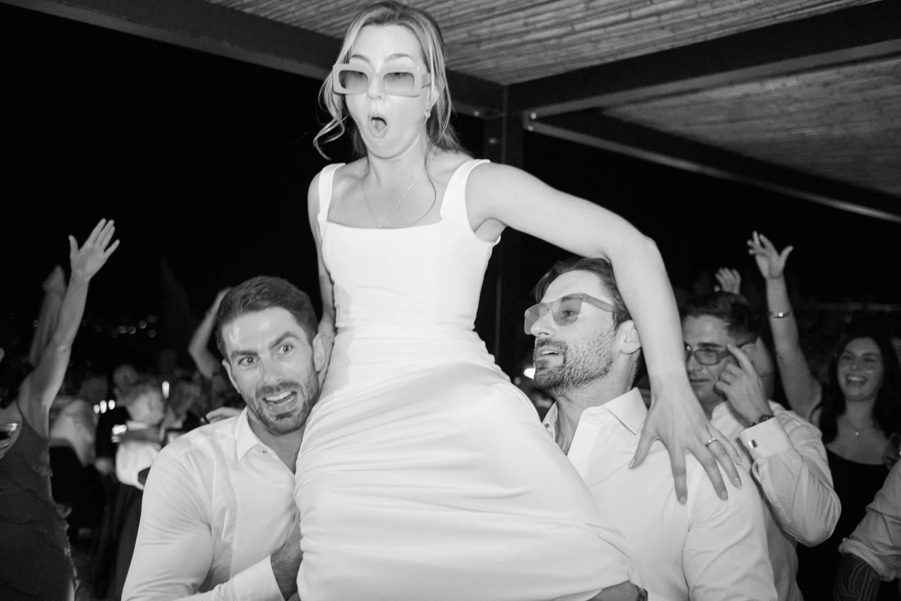 La sposa sollevata dagli amici durante la festa, in bianco e nero
