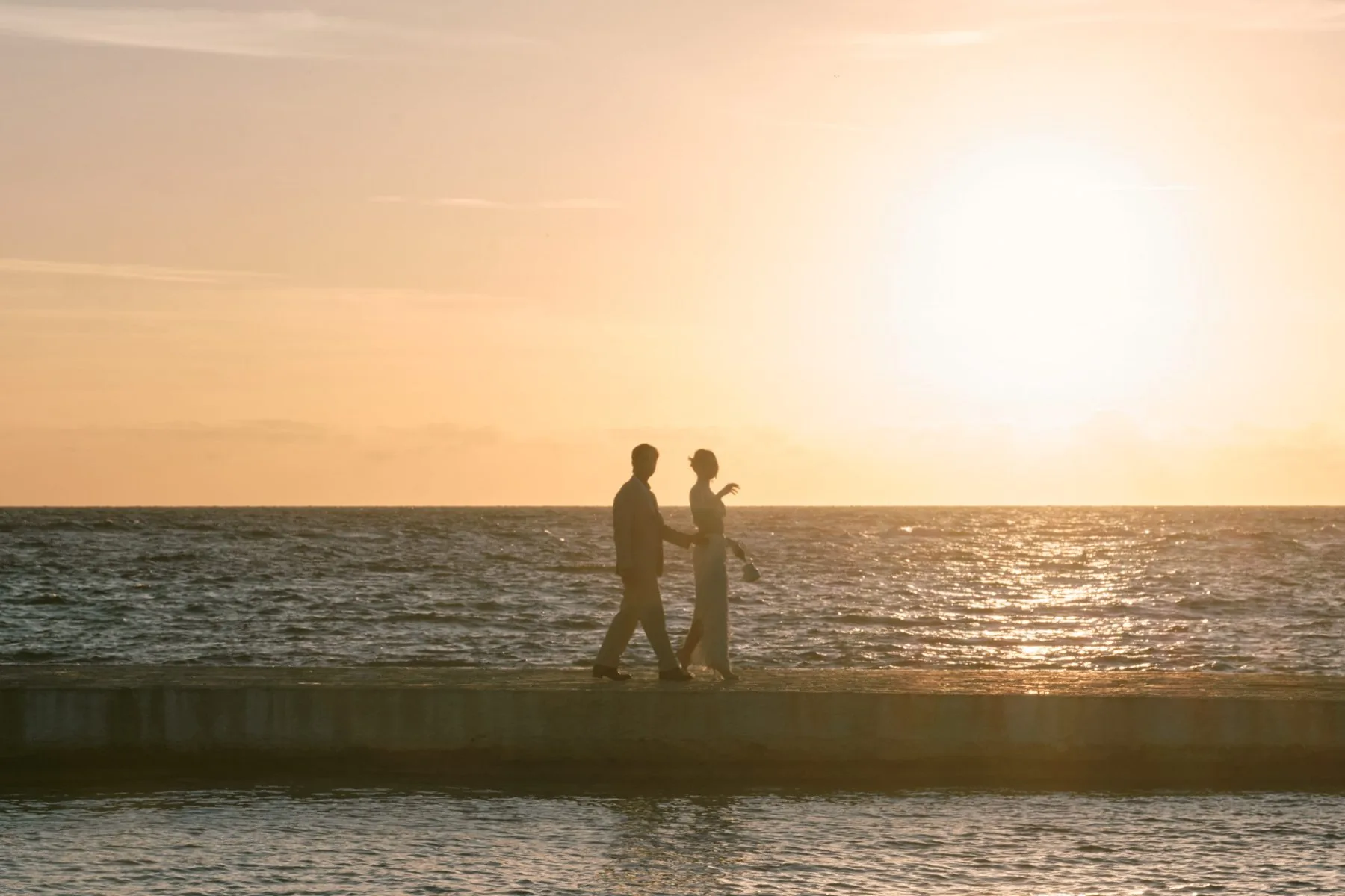 La silhouette di Erica e Ged contro il mare al tramonto