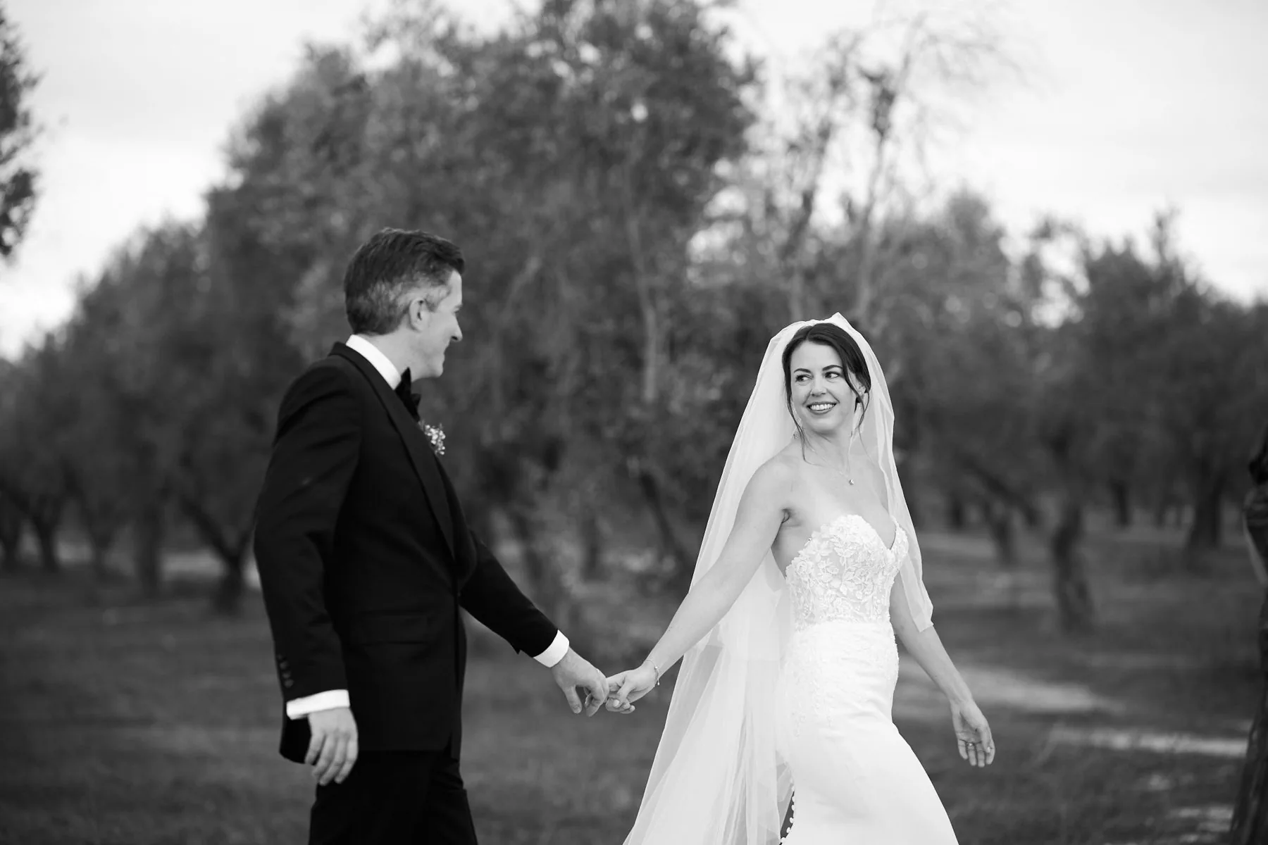 Katy e Gregory mano nella mano tra gli ulivi, in bianco e nero